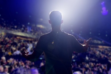 Image of Man performing on stage of concert hall crowded with people