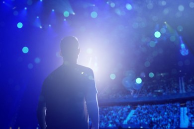 Image of Man performing on stage of concert hall crowded with people