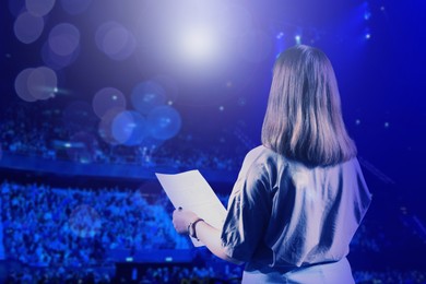 Image of Woman performing on stage of concert hall crowded with people