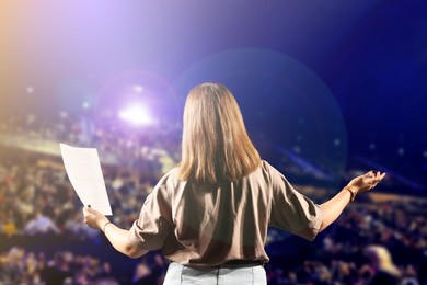 Image of Woman performing on stage of concert hall crowded with people