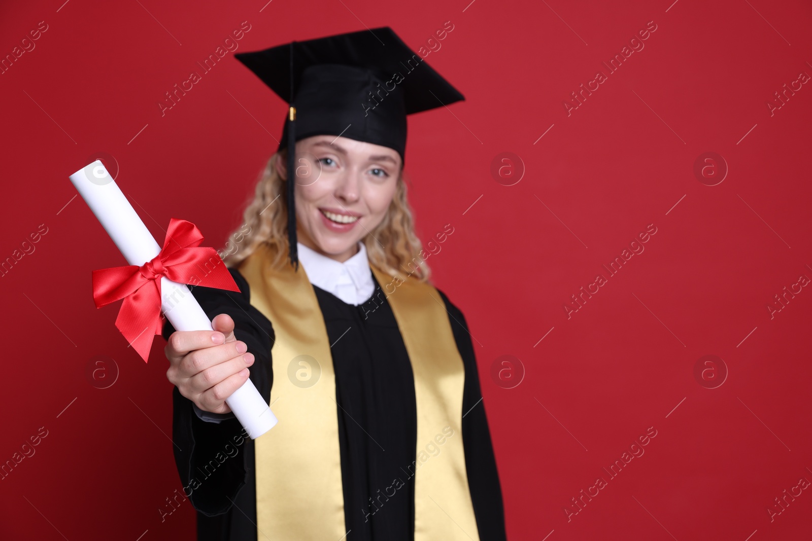 Happy student with diploma after graduation on red background, selective focus. Space for text Photo of Happy student with diploma after graduation on red background, selective focus. Space for text