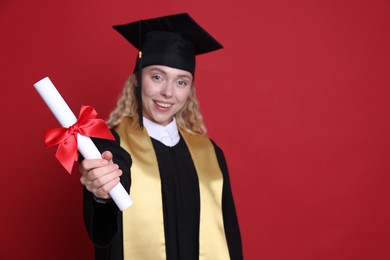 Photo of Happy student with diploma after graduation on red background, selective focus. Space for text