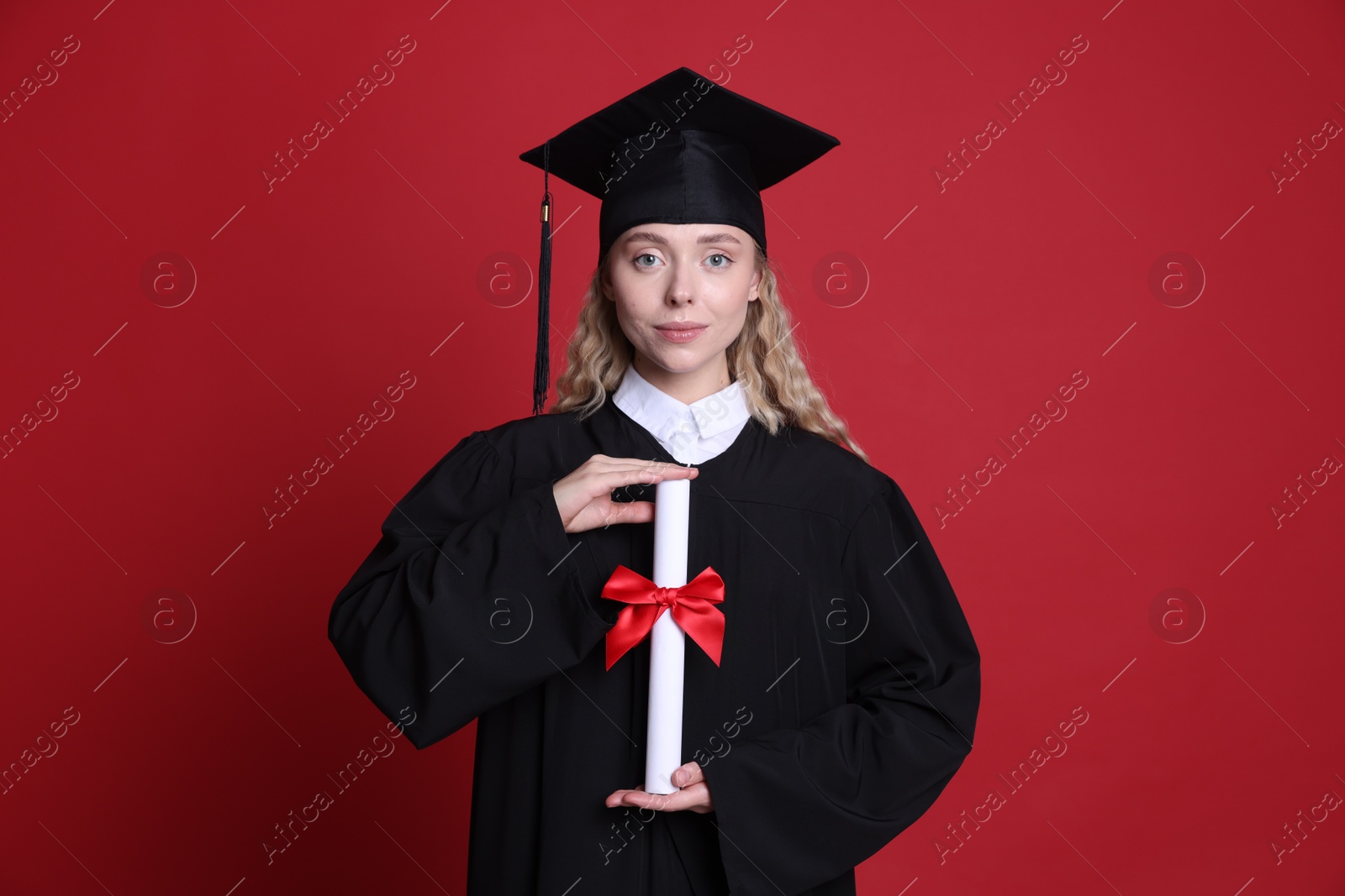 Student with diploma after graduation on red background Photo of Student with diploma after graduation on red background