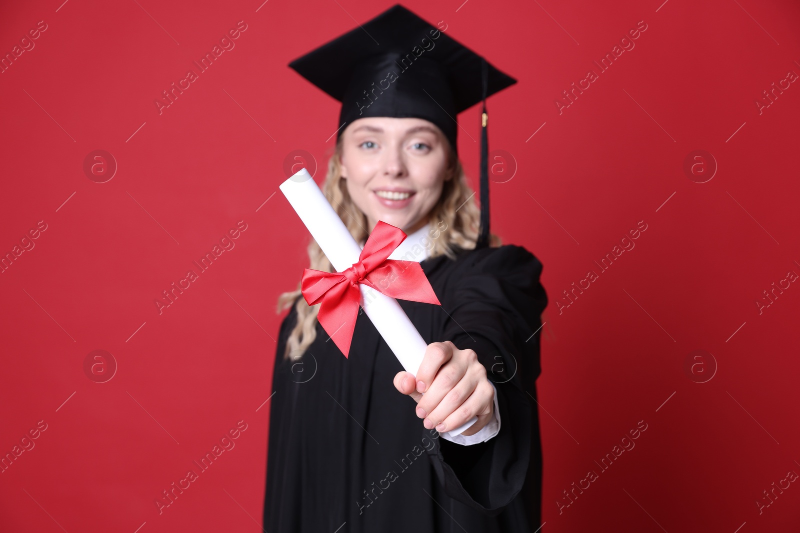 Happy student with diploma after graduation on red background, selective focus Photo of Happy student with diploma after graduation on red background, selective focus