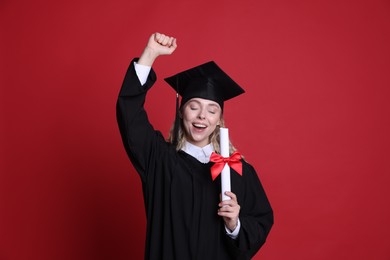 Photo of Happy student with diploma after graduation on red background