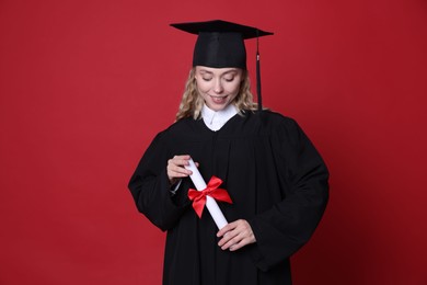 Photo of Happy student with diploma after graduation on red background