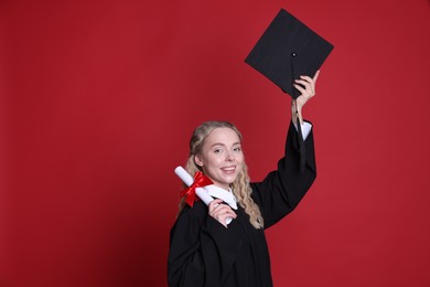 Photo of Happy student with diploma and mortarboard after graduation on red background