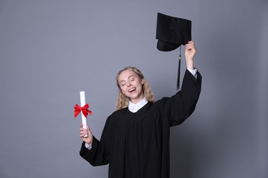 Photo of Happy student with diploma and mortarboard after graduation on grey background