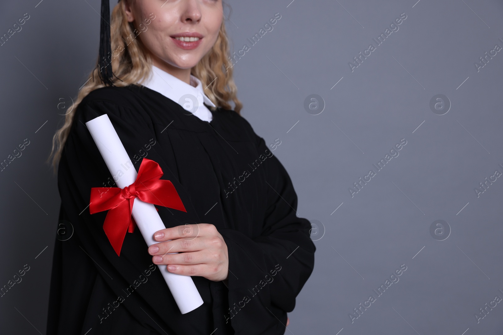 Happy student with diploma after graduation on grey background, closeup. Space for text Photo of Happy student with diploma after graduation on grey background, closeup. Space for text