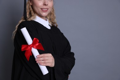 Photo of Happy student with diploma after graduation on grey background, closeup. Space for text