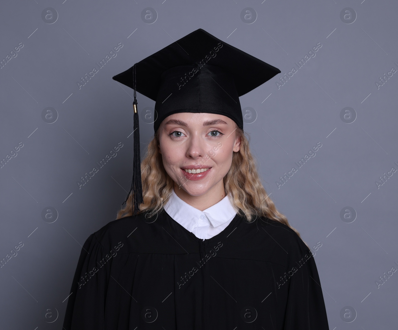 Happy student after graduation on grey background Photo of Happy student after graduation on grey background