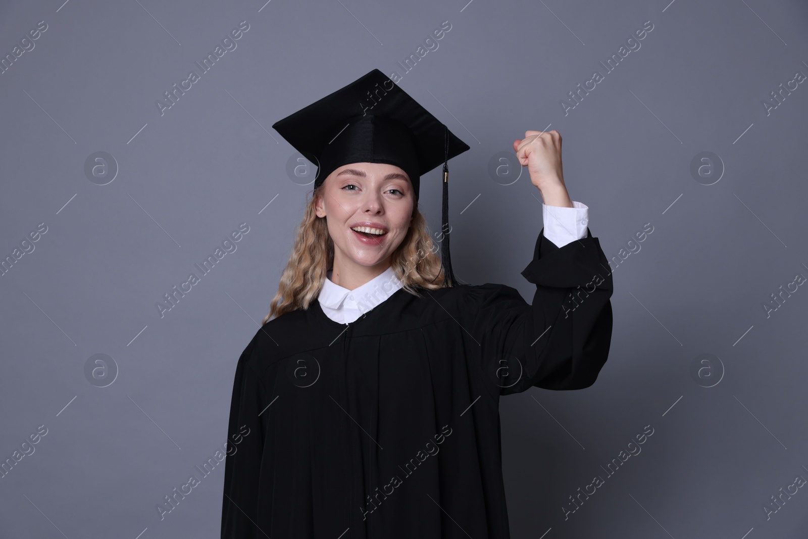 Happy student after graduation on grey background Photo of Happy student after graduation on grey background
