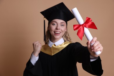 Photo of Happy student with diploma after graduation on beige background, selective focus