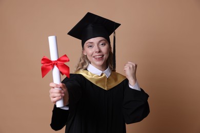 Photo of Happy student with diploma after graduation on beige background, selective focus