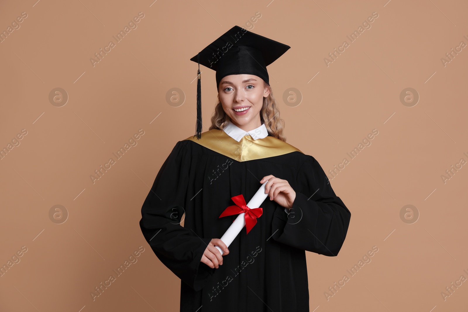 Happy student with diploma after graduation on beige background Photo of Happy student with diploma after graduation on beige background