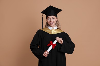 Photo of Happy student with diploma after graduation on beige background