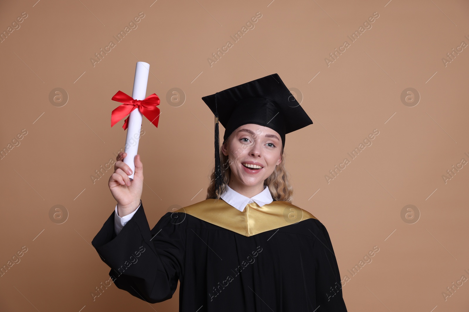 Happy student with diploma after graduation on beige background Photo of Happy student with diploma after graduation on beige background