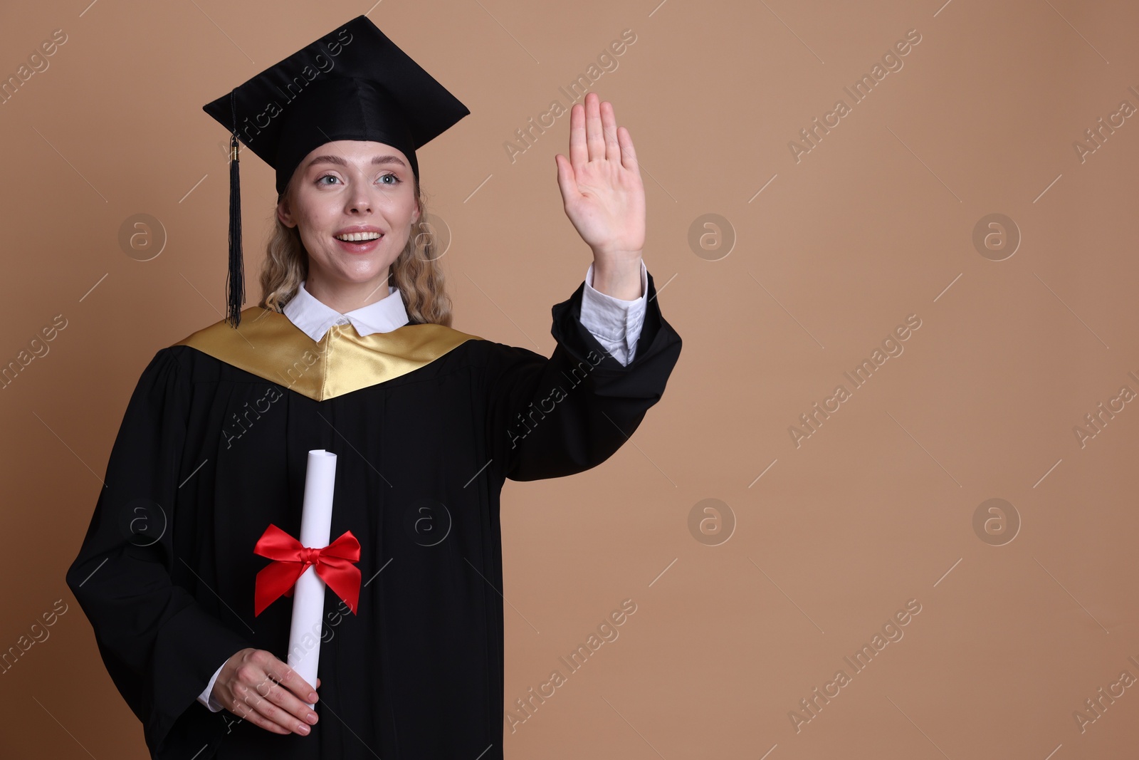 Happy student with diploma after graduation waving on beige background. Space for text Photo of Happy student with diploma after graduation waving on beige background. Space for text