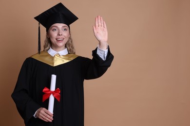 Photo of Happy student with diploma after graduation waving on beige background. Space for text