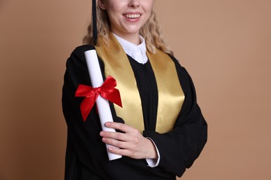 Photo of Happy student with diploma after graduation on beige background, closeup