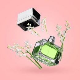 Image of Lilies of the valley and bottle of perfume in air on pink background