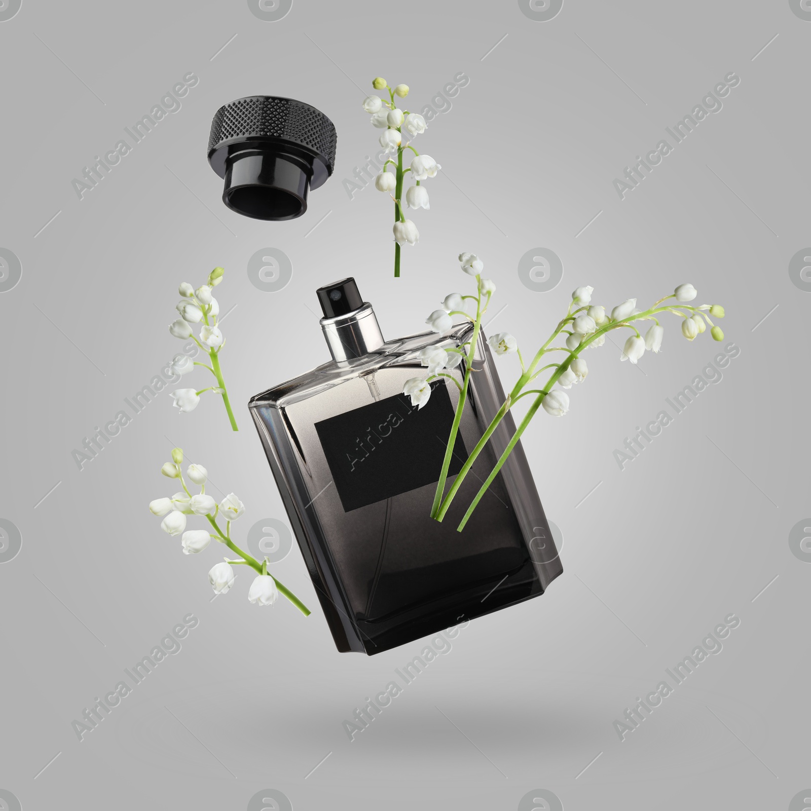 Lilies of the valley and bottle of perfume in air on grey background Image of Lilies of the valley and bottle of perfume in air on grey background