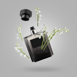 Image of Lilies of the valley and bottle of perfume in air on grey background
