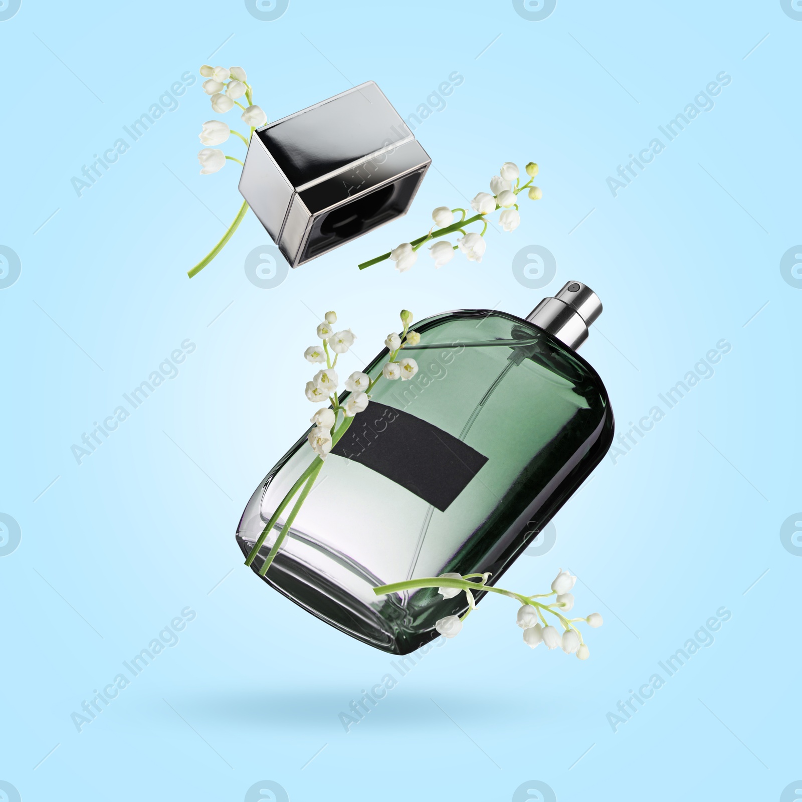 Lilies of the valley and bottle of perfume in air on light blue background Image of Lilies of the valley and bottle of perfume in air on light blue background