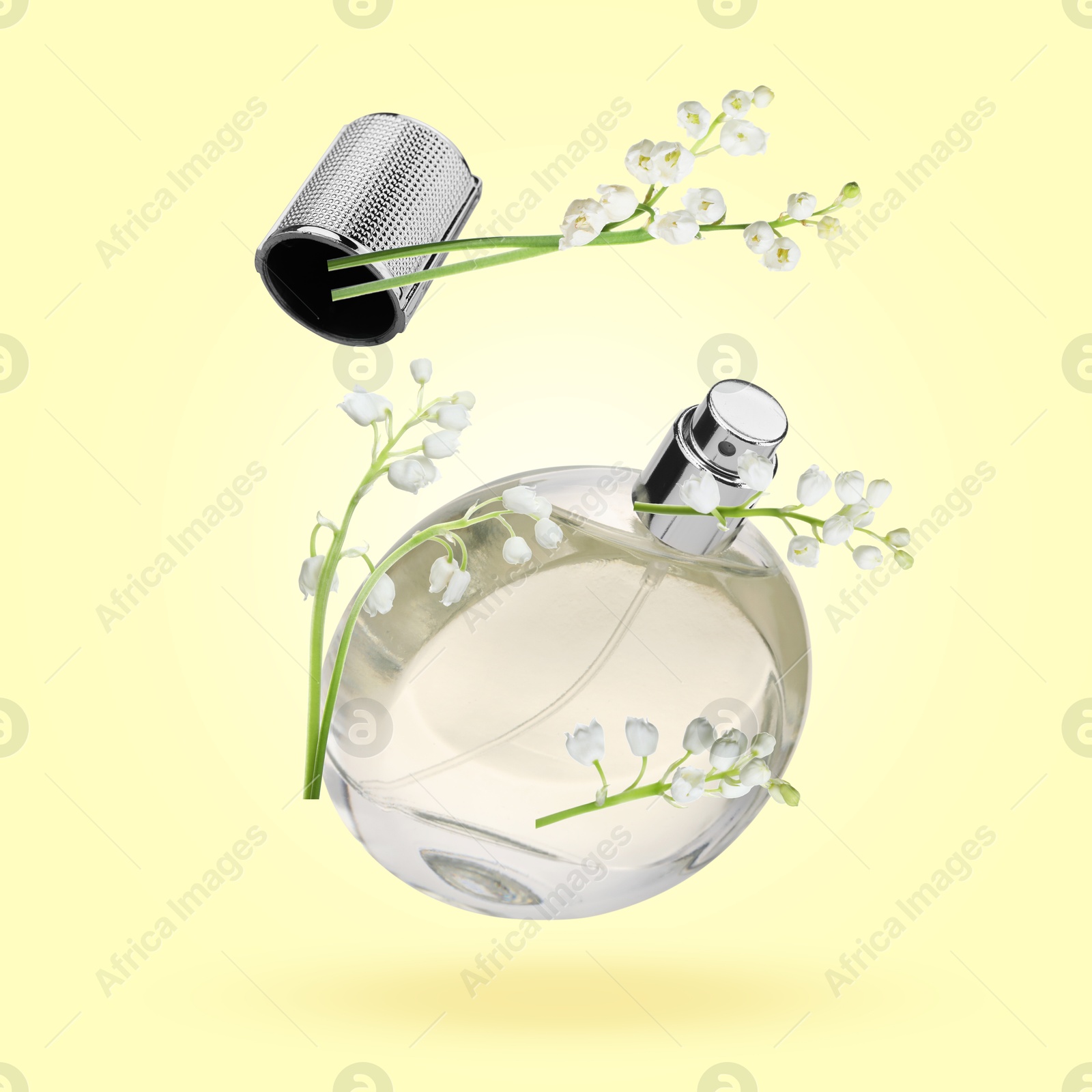 Lilies of the valley and bottle of perfume in air on light yellow background Image of Lilies of the valley and bottle of perfume in air on light yellow background