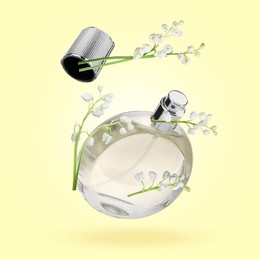 Image of Lilies of the valley and bottle of perfume in air on light yellow background