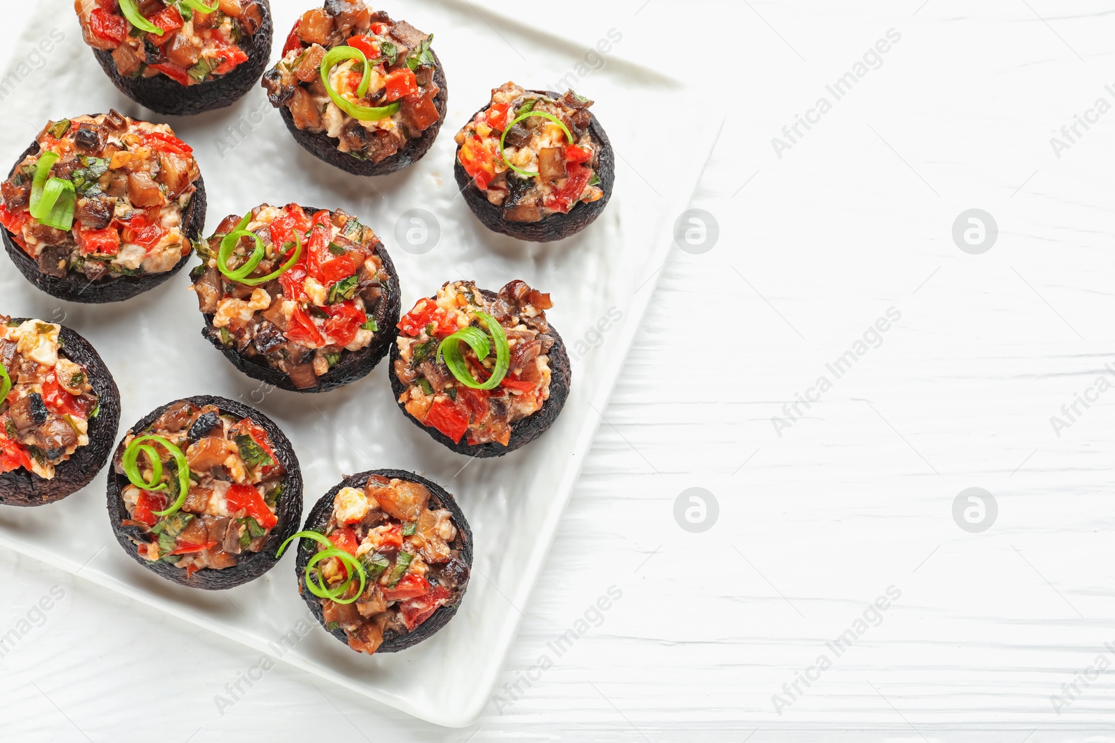 Delicious stuffed mushrooms on white wooden table, top view. Space for text Photo of Delicious stuffed mushrooms on white wooden table, top view. Space for text