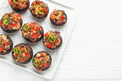 Photo of Delicious stuffed mushrooms on white wooden table, top view. Space for text