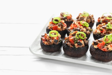 Photo of Delicious stuffed mushrooms on white wooden table, closeup. Space for text