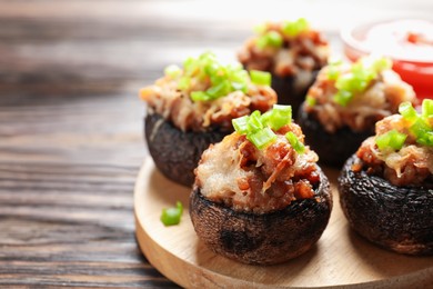 Photo of Delicious stuffed mushrooms and sauce on wooden table, closeup. Space for text
