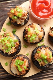 Photo of Delicious stuffed mushrooms and sauce on wooden table, top view