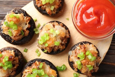 Photo of Delicious stuffed mushrooms and sauce on wooden table, top view