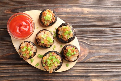 Photo of Delicious stuffed mushrooms and sauce on wooden table, top view. Space for text