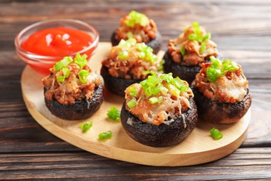 Photo of Delicious stuffed mushrooms and sauce on wooden table, closeup