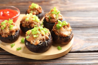 Photo of Delicious stuffed mushrooms and sauce on wooden table, closeup. Space for text