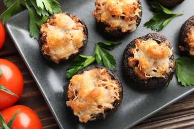 Photo of Delicious stuffed mushrooms with parsley and tomatoes on wooden table, flat lay