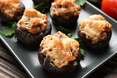 Photo of Delicious stuffed mushrooms with parsley on wooden table, closeup