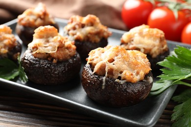 Photo of Delicious stuffed mushrooms with parsley and tomatoes on table, closeup