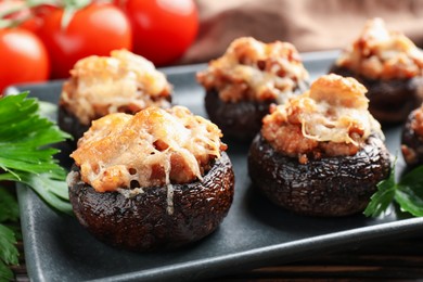 Photo of Delicious stuffed mushrooms with parsley and tomatoes on table, closeup