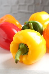 Photo of Ripe colorful bell peppers on white table, closeup