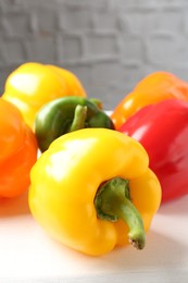 Photo of Ripe colorful bell peppers on white table, closeup