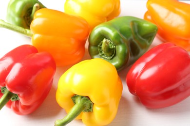 Photo of Ripe colorful bell peppers on white table, closeup