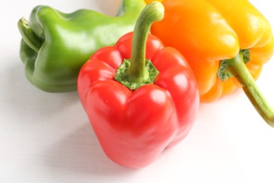 Photo of Ripe colorful bell peppers on white table, closeup