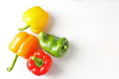 Photo of Ripe colorful bell peppers on white table, flat lay. Space for text
