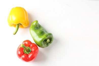 Photo of Ripe colorful bell peppers on white table, flat lay. Space for text