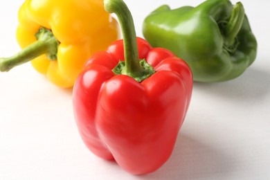 Photo of Ripe colorful bell peppers on white table, closeup